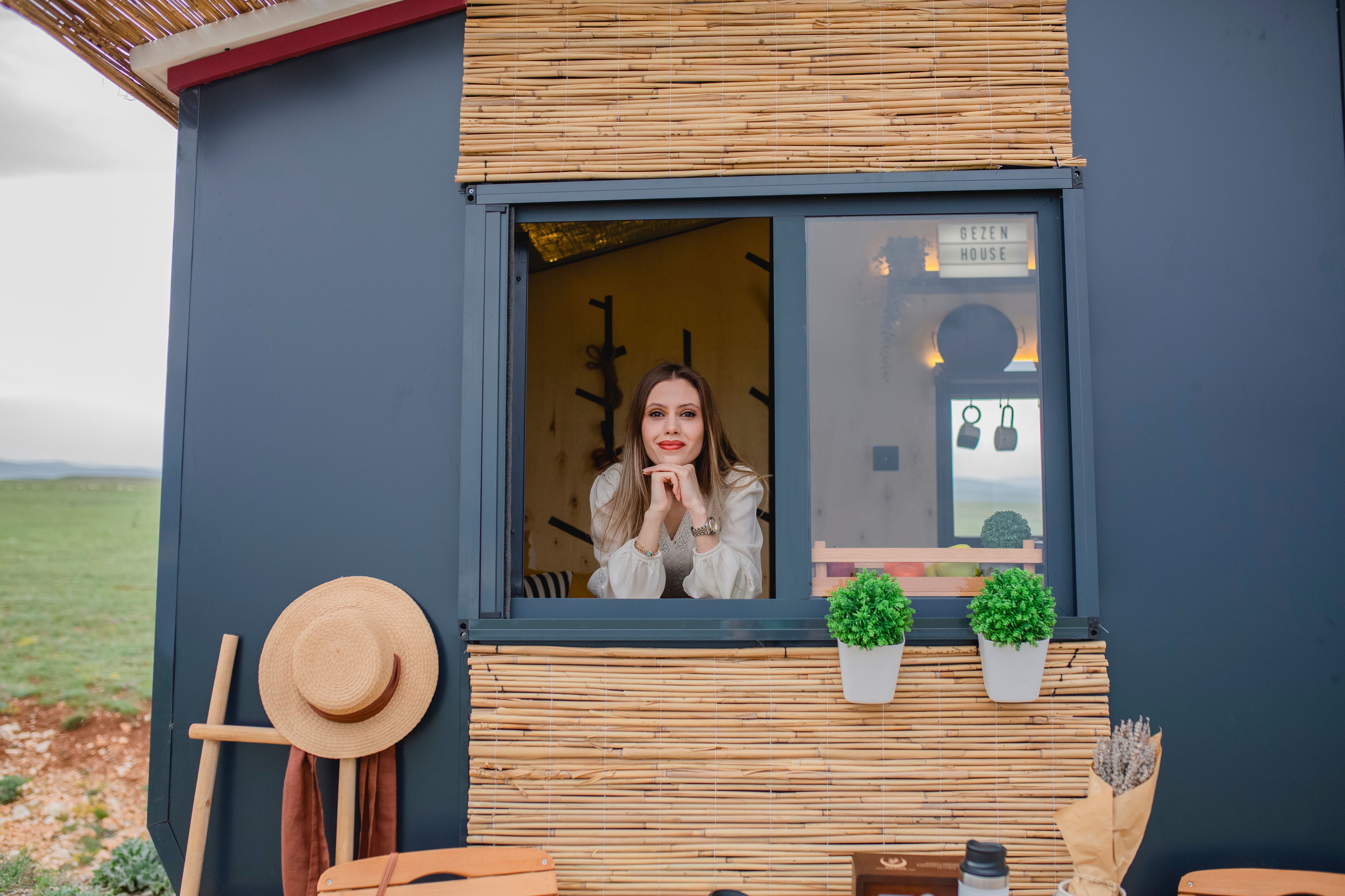 Junge Frau schaut aus Fenster blaues Tiny House